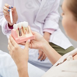 Dentist showing patient model of dental implant