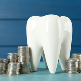 a ceramic model of tooth and coins on a light blue wooden table
