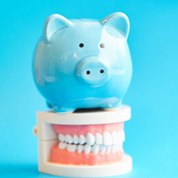 model teeth with a piggy bank on a blue background
