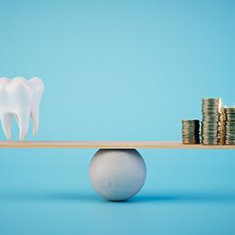 Fake tooth and a pile of coins balancing on a rudimentary scale
