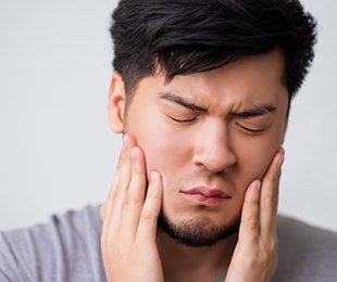 Man in pain touching the sides of his face